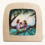 Toverlux Magic Lamp Silhouette - Artwork By Het Wol Feetje, Siblings. Three felt children are sat in a large tree, on the tree branch and are looking at each other. The image is on a cream background