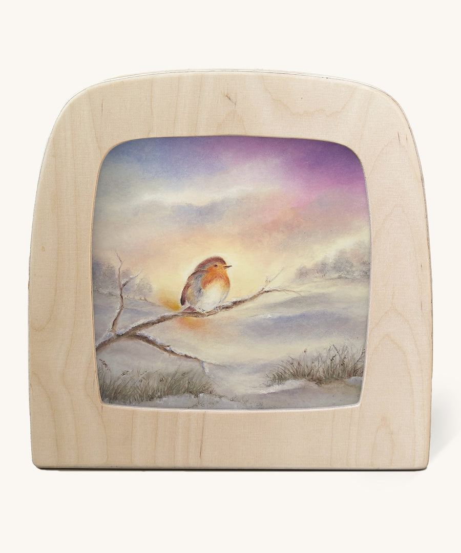 Winter Robin Toverlux Magic Lamp Silhouette - Artwork By Baukje Exler. A lovely little robin is sat on a snowy covered tree branch, with a snowy woodland background in the illustration, in tones of white, grey and purple. The image is on a cream background