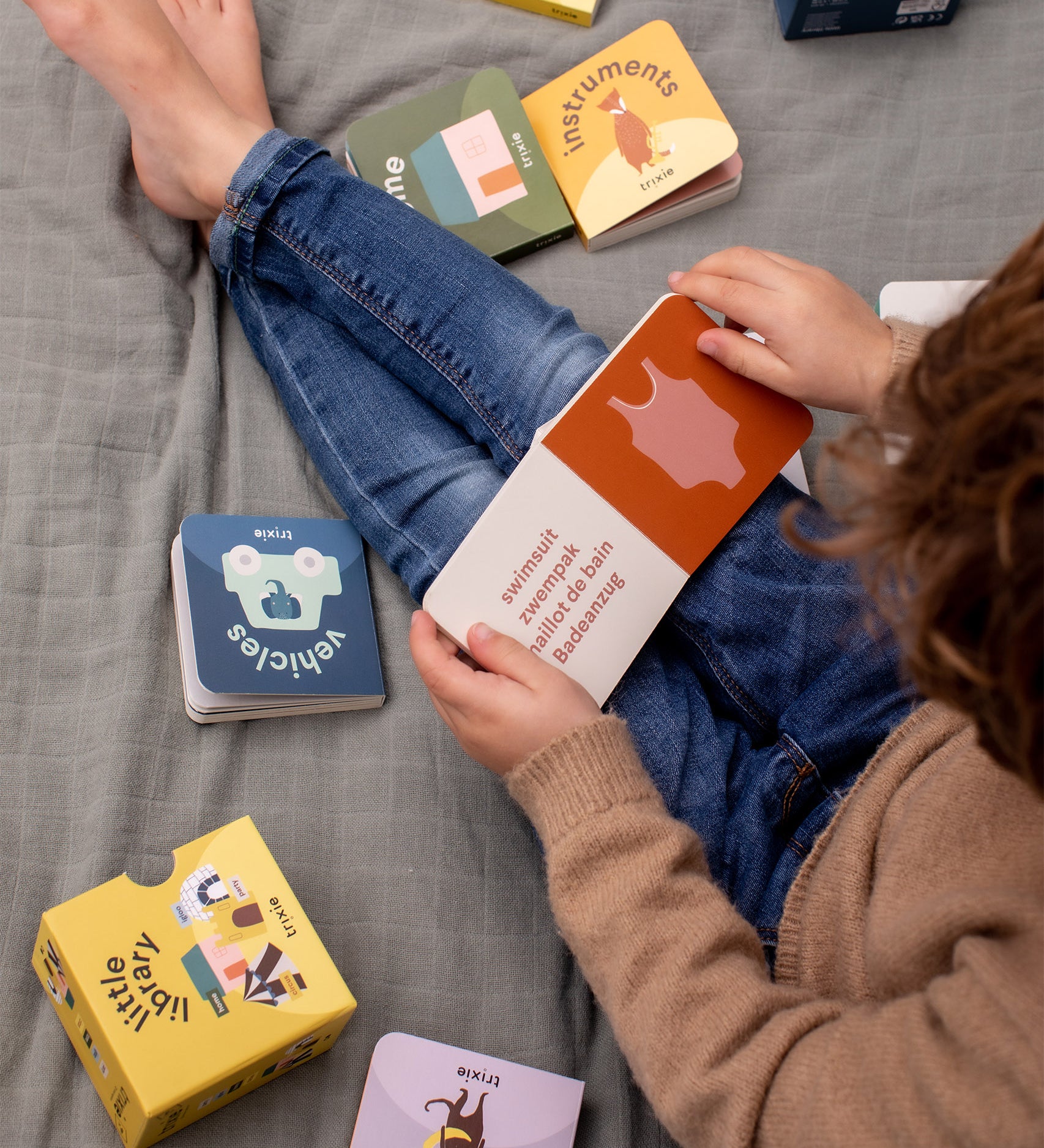 Child sat on a blanket reading Trixie Little Library board books.