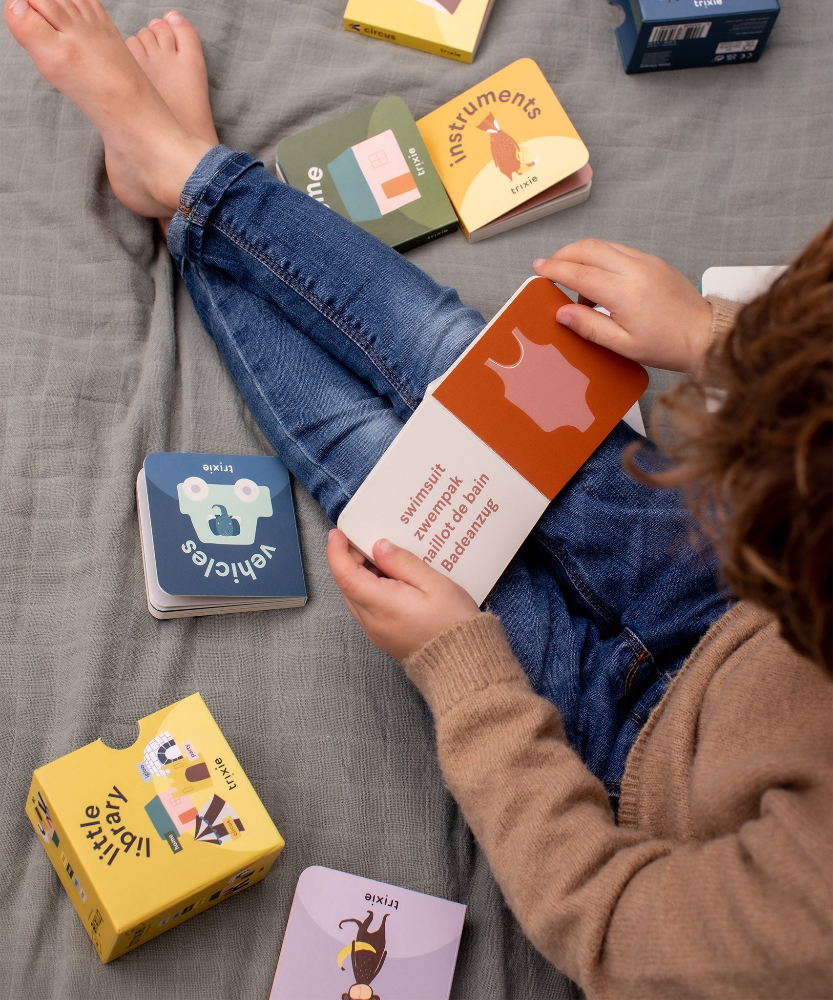 Child sat on a blanket reading Trixie Little Library board books.