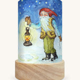 The Winter Gnome illustration by Eentje Van Margo sat in a Toverlux Magic Lantern base, on a cream background