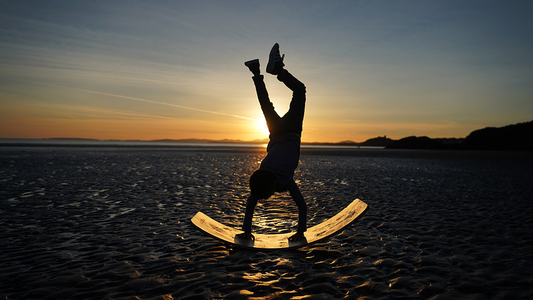 Child doing a handstand on a Wobbel board on the beach