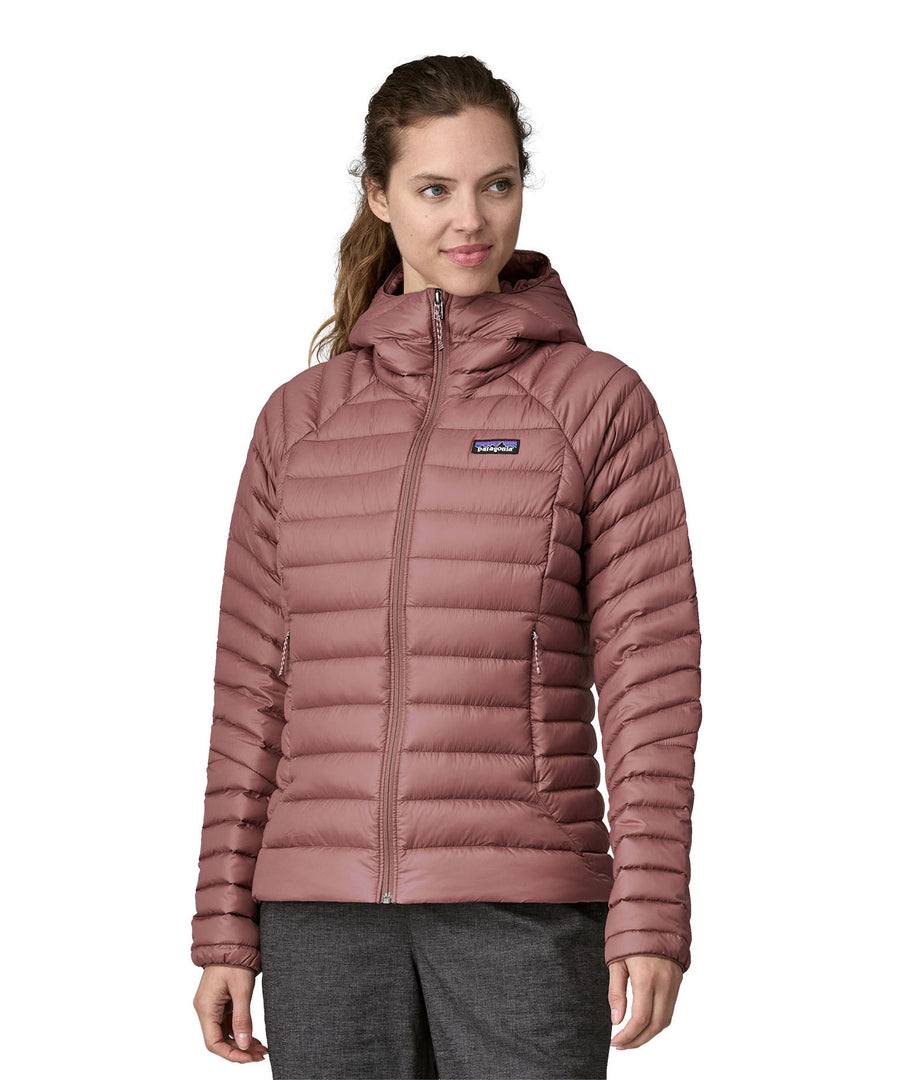 A person wearing the Patagonia Women's Down Sweater Hoody - Dulse Mauve. Perfect for cooler weather