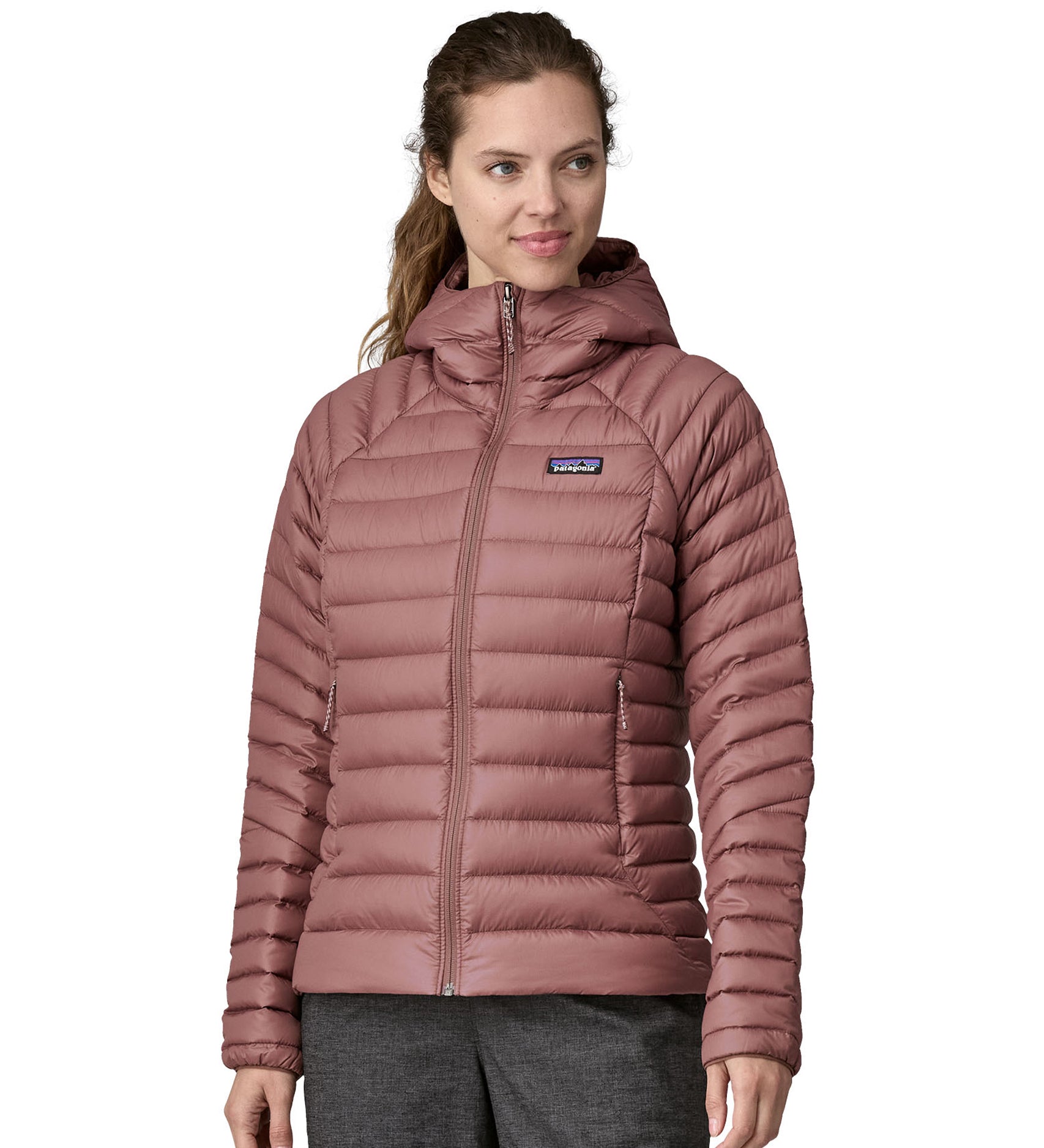 A person wearing the Patagonia Women's Down Sweater Hoody - Dulse Mauve. Perfect for cooler weather