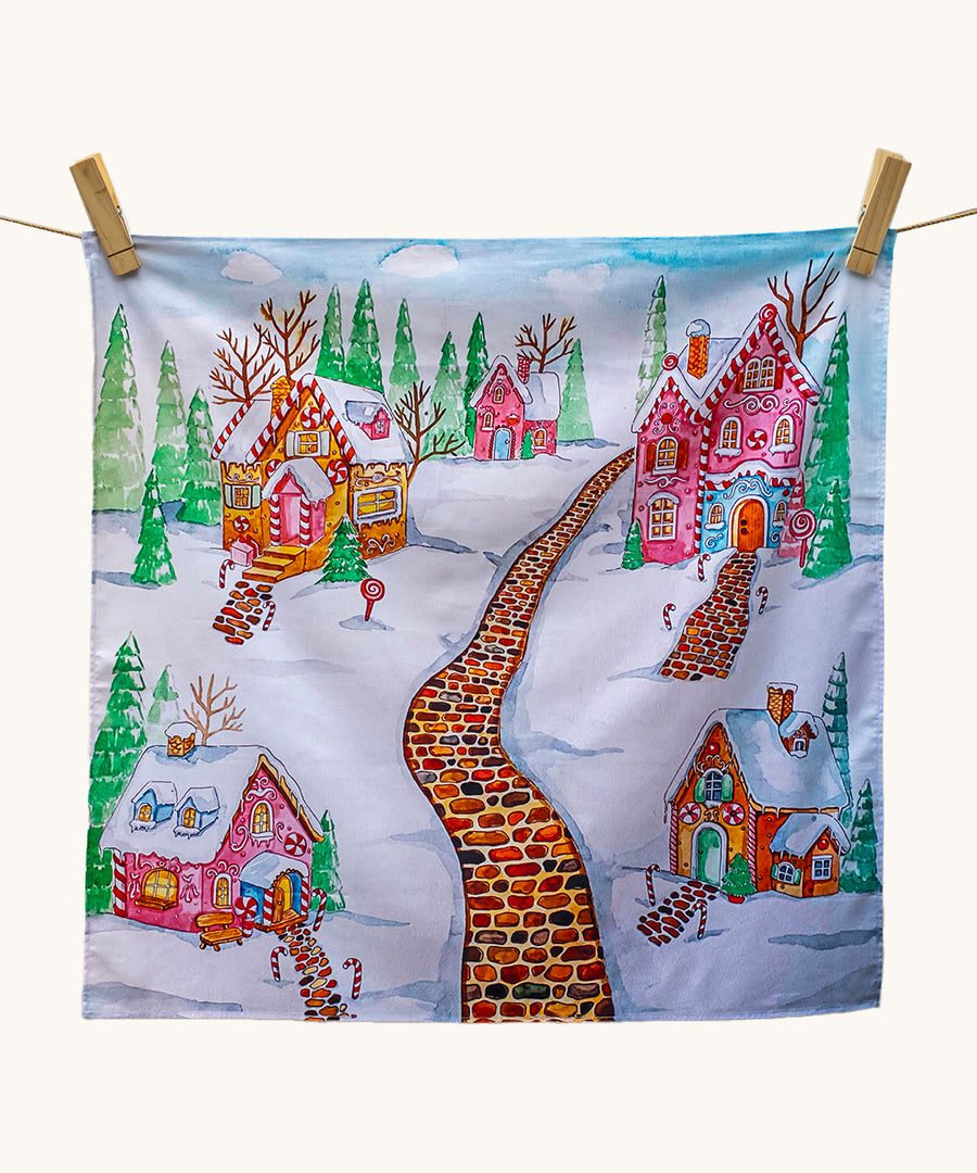 Wonderie Play Cloth - Gingerbread Lane, is a lovey sensory play cloth with 
a beautifully hand-illustrated festive scene, featuring a red brick path through a snowy village filled with enchanting gingerbread houses, with sugar icing roofs, candy canes lining the paths and snow-covered fir trees