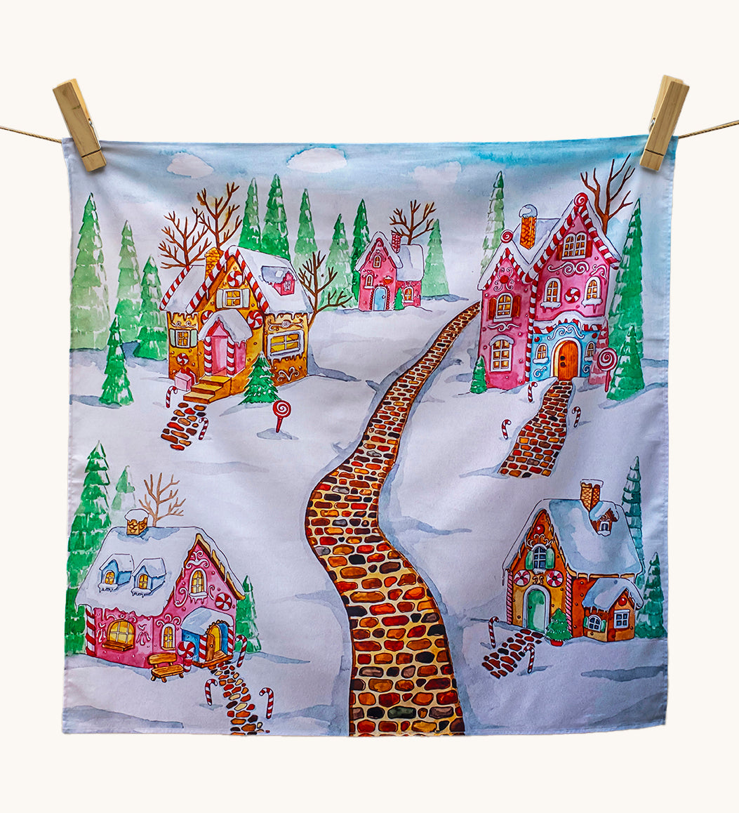 Wonderie Play Cloth - Gingerbread Lane, is a lovey sensory play cloth with 
a beautifully hand-illustrated festive scene, featuring a red brick path through a snowy village filled with enchanting gingerbread houses, with sugar icing roofs, candy canes lining the paths and snow-covered fir trees