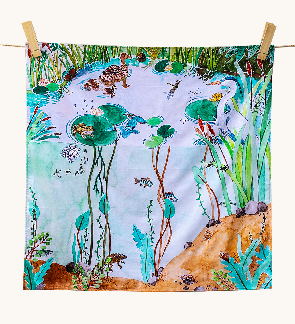 Wonderie Play Cloth - Down By The Pond. A beautiful play cloth depicting a busy pond scene with ducks, frogs, a heron, fish and dragonflies all playing among the reeds and lily pads