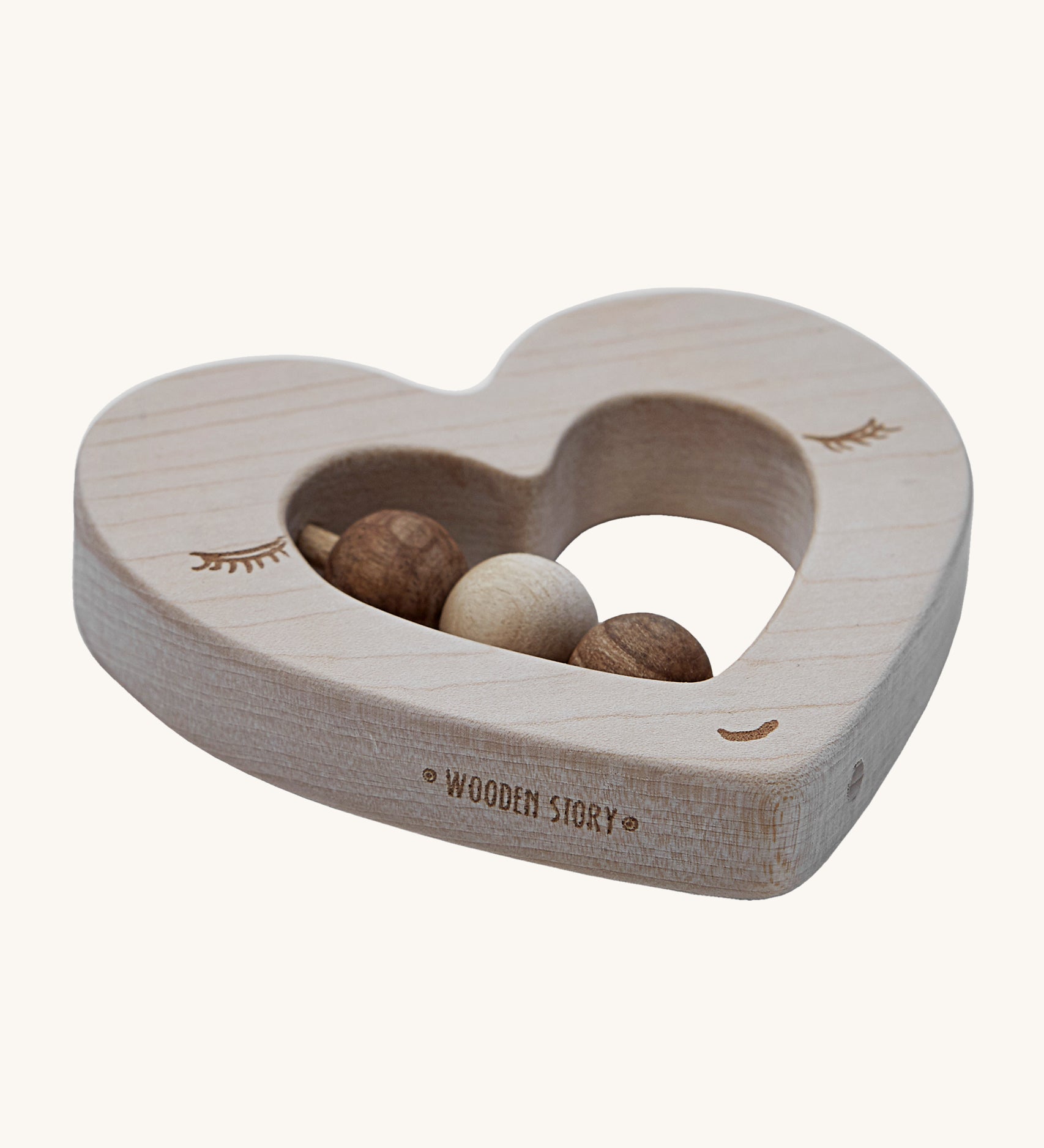 A side view of the Wooden Story Heart Rattle, showing the natural wood grain of the rattle, and the words "Wooden Story" etched onto the side of the rattle.