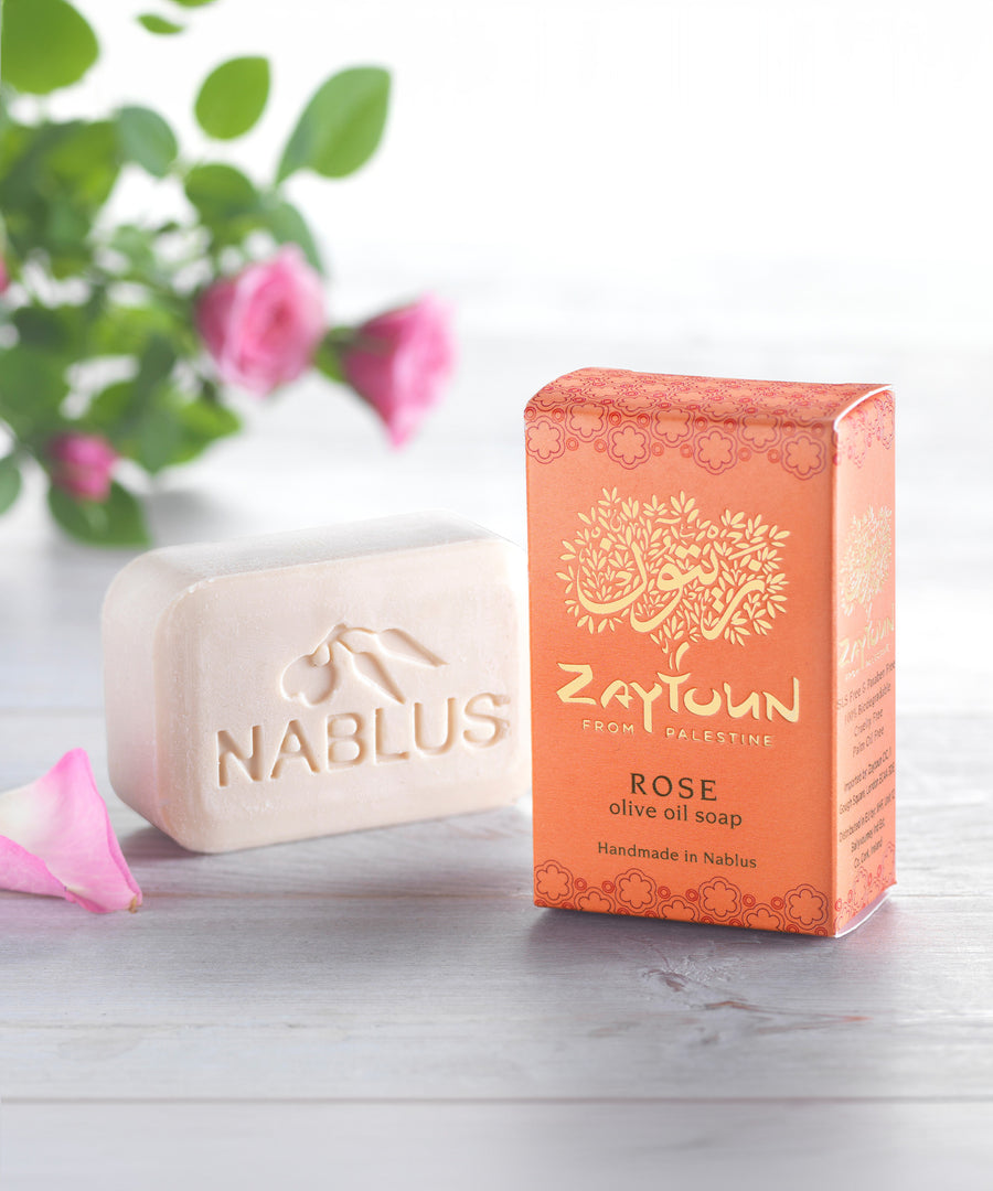 Zaytoun Pure Olive Oil Soap - Rose 100g. A beautiful rose scented Nablus soap bar, stood next to the box with a rose plant in the background