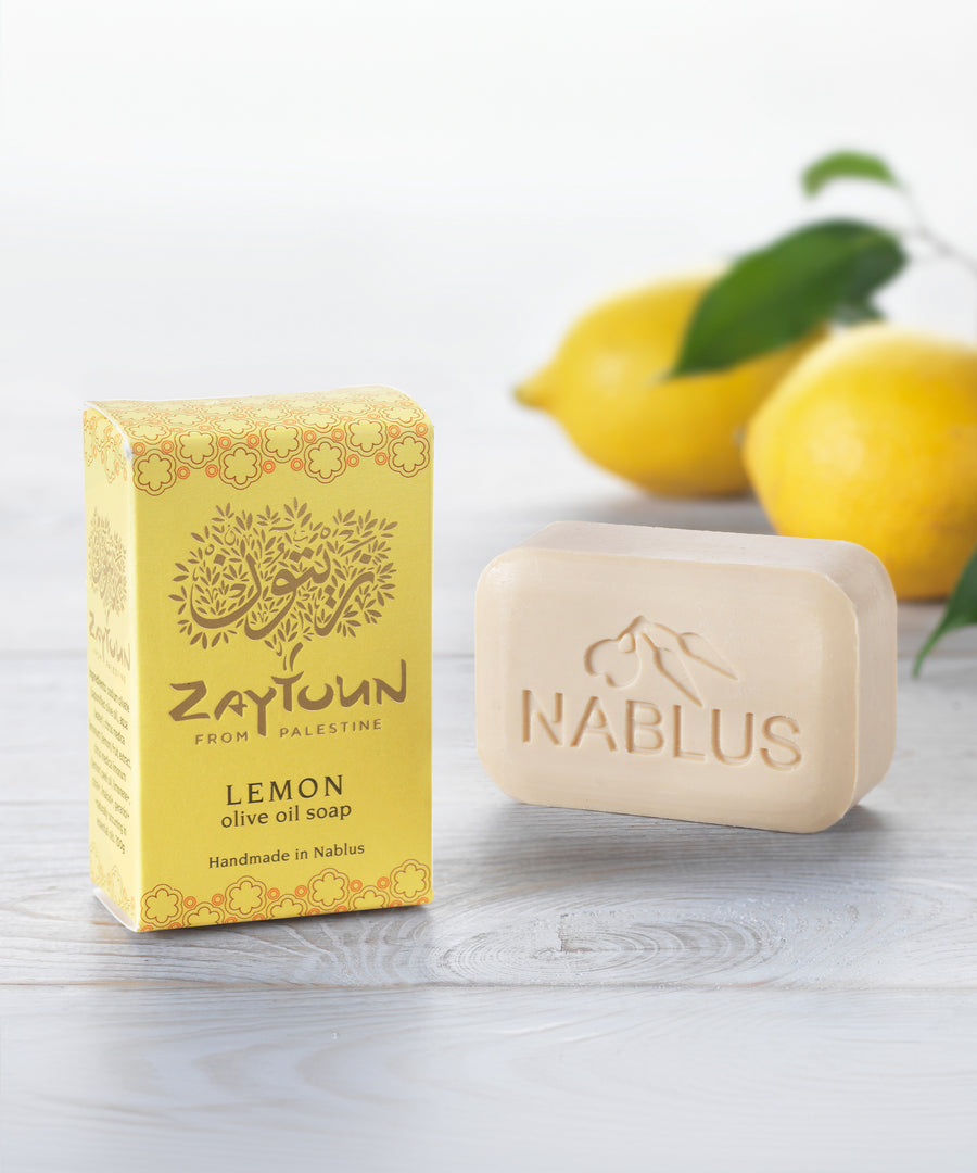 Zaytoun Pure Olive Oil Soap - Lemon 100g, next to its box and stood in front of a pair of lemons