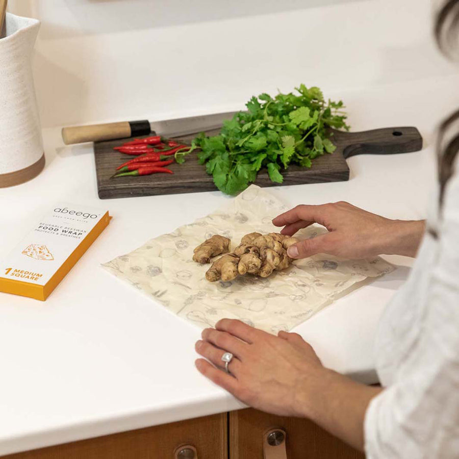 Hands wrapping up some ginger in a medium Abeego plastic-free reusable food wrap