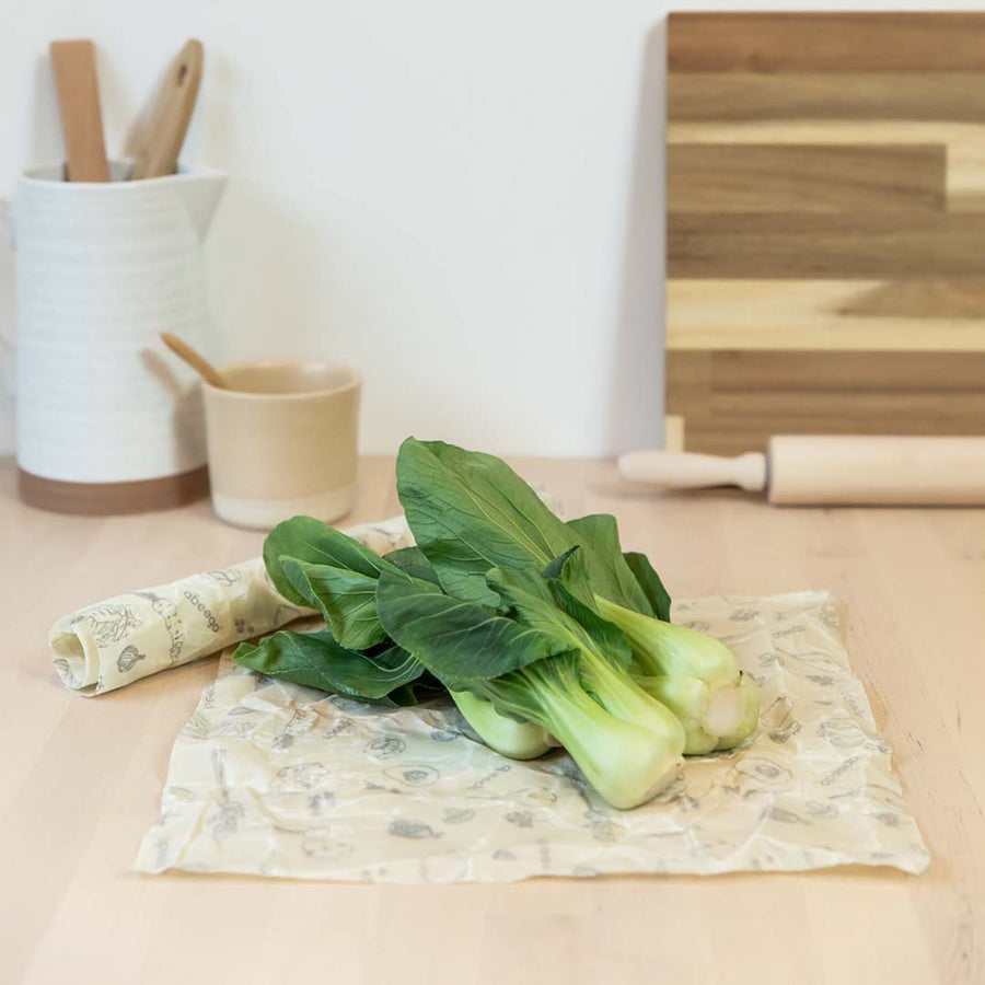 Vegetables laid out on an Abeego large square beeswax food wraps on a wooden worktop