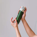 Close up of hands holding a cucumber with the end wrapped in an Abeego reusable plastic-free beeswax wrap