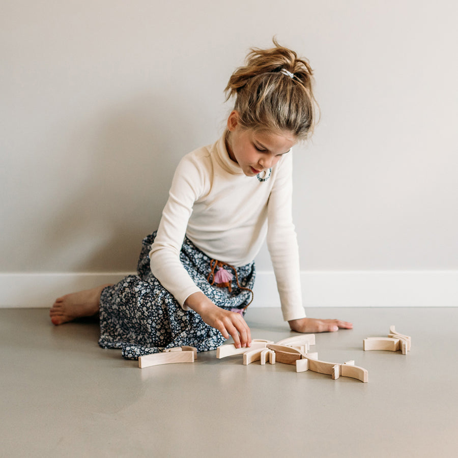 Girl sat on the floor playing with the Abel plastic-free Golden Ratio toy blocks set