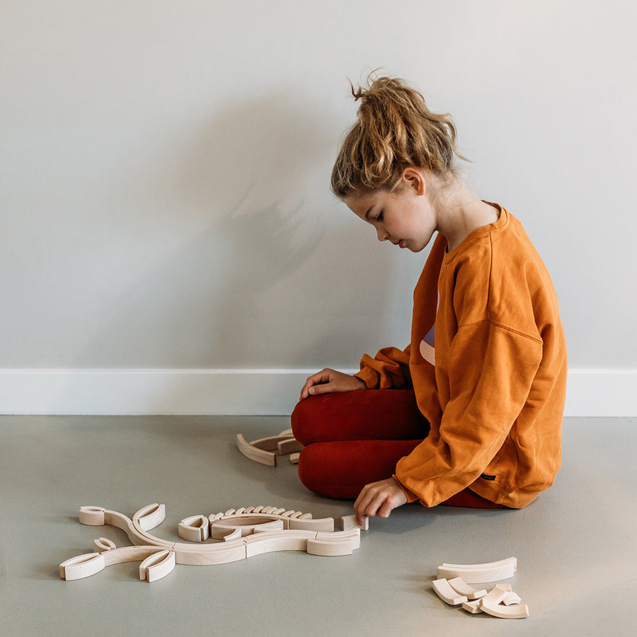 Girl sat on the floor playing with the 48 pack of Abel curved wooden Golden Ratio toy blocks