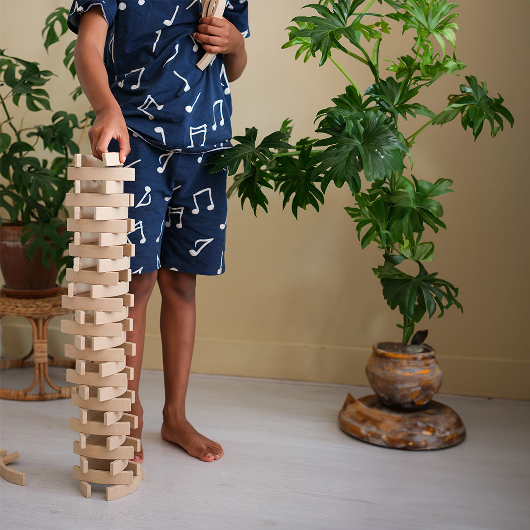 Picture of the Abel Blocks Mini Re-Wood stacked into a tall geometrical tower by a child.