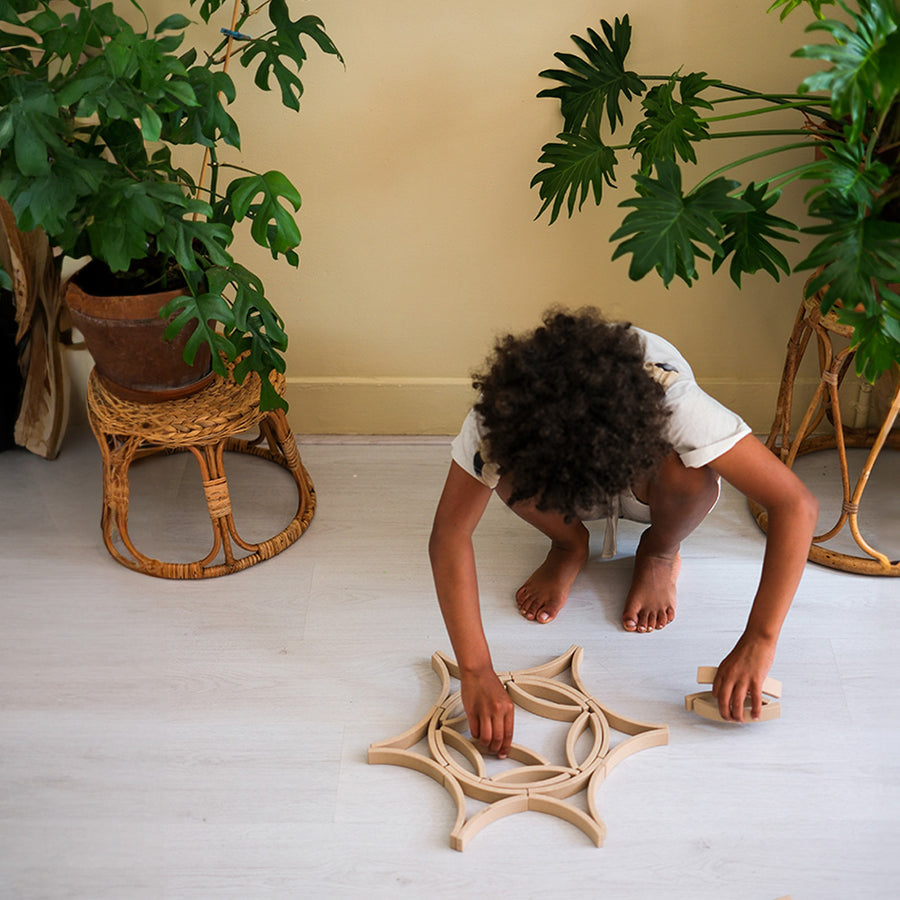 The set of 24 Abel Mini Re-Wood blocks being placed in a mandala pattern by a child.