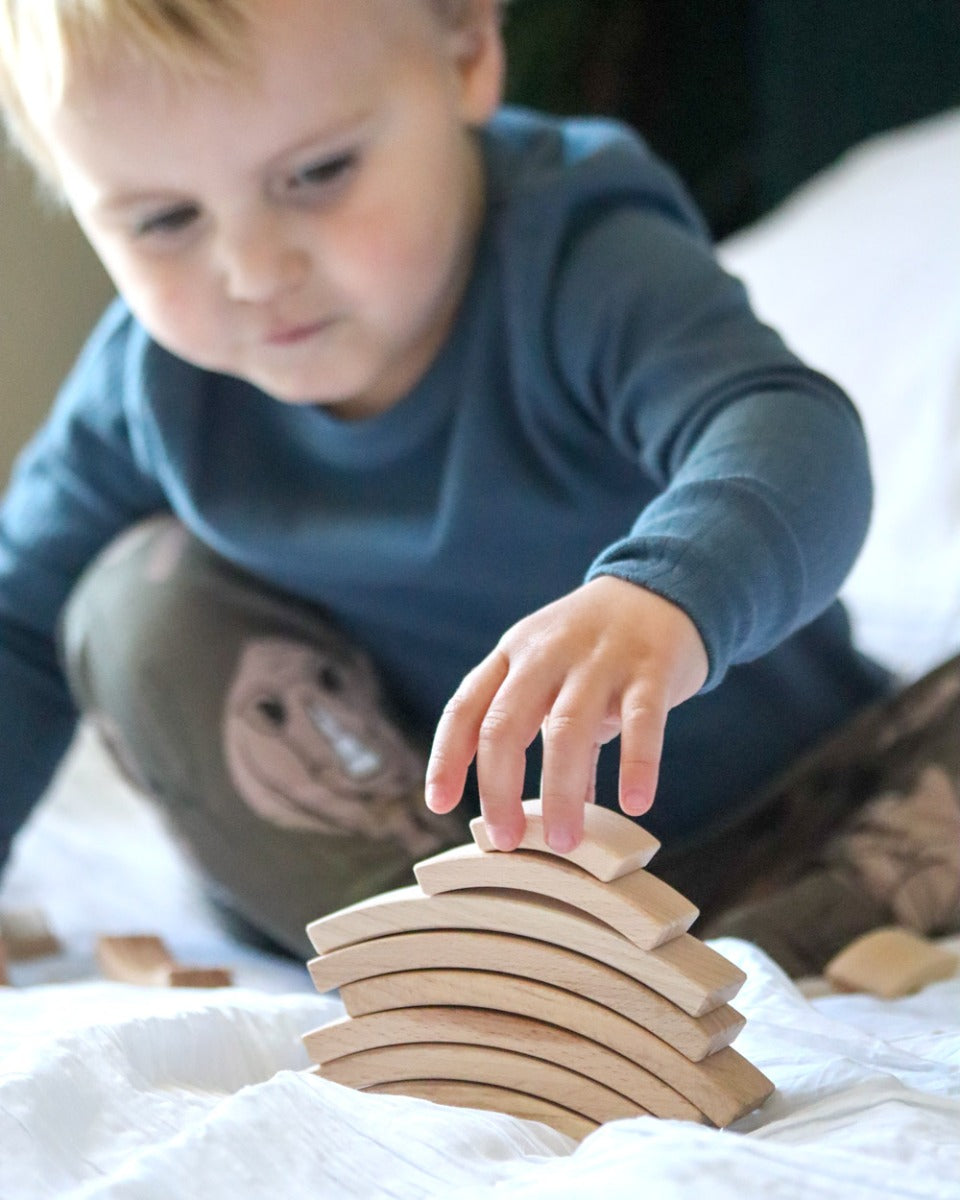 Young boy stacking the Abel plastic-free Golden Ratio toy blocks on a white sheet