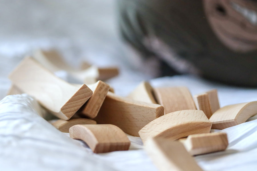 Close up of a pile of Abel plastic-free wooden Golden Ratio toy blocks on a white bed