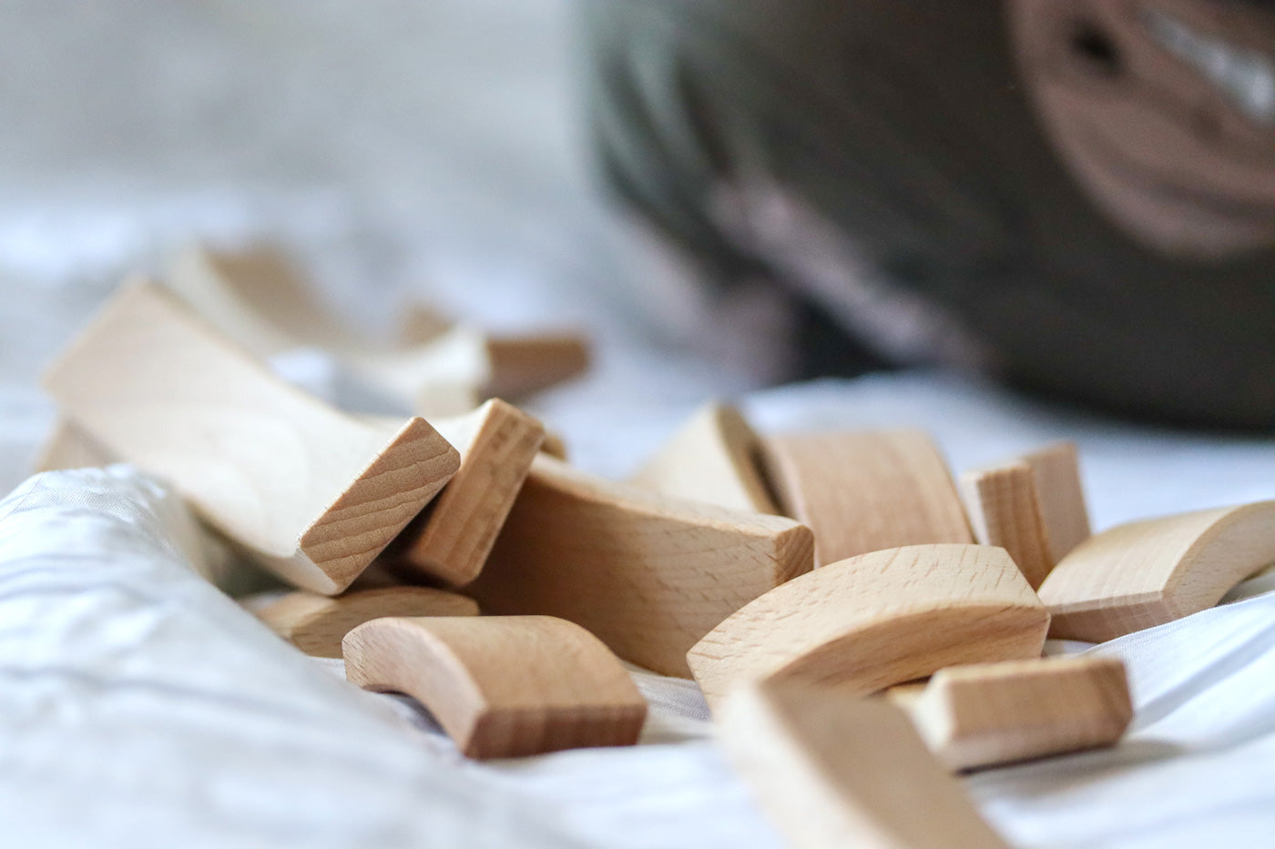 Close up of a pile of Abel Golden Ratio stacking wooden toy blocks on a white bed