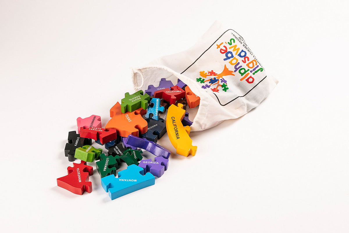 Alphabet Jigsaw plastic-free Map of USA pieces pouring out of a white drawstring bag on a white background