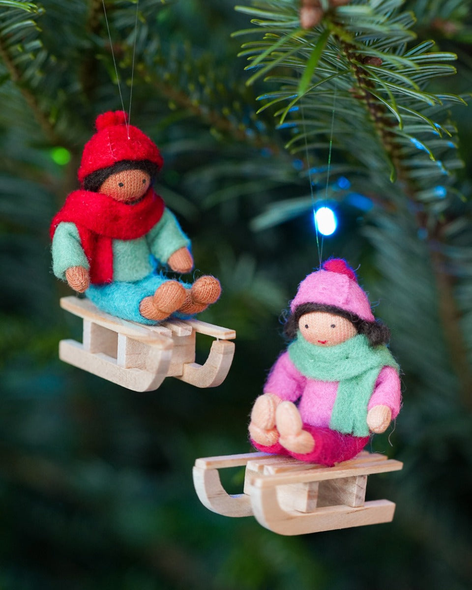 Ambrosius collectable boy on sledge Christmas decoration hanging from a stick on a white background