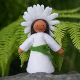 Close up of the Ambrosius oxeye daisy crown fairy doll on a rock in front of a green plant background