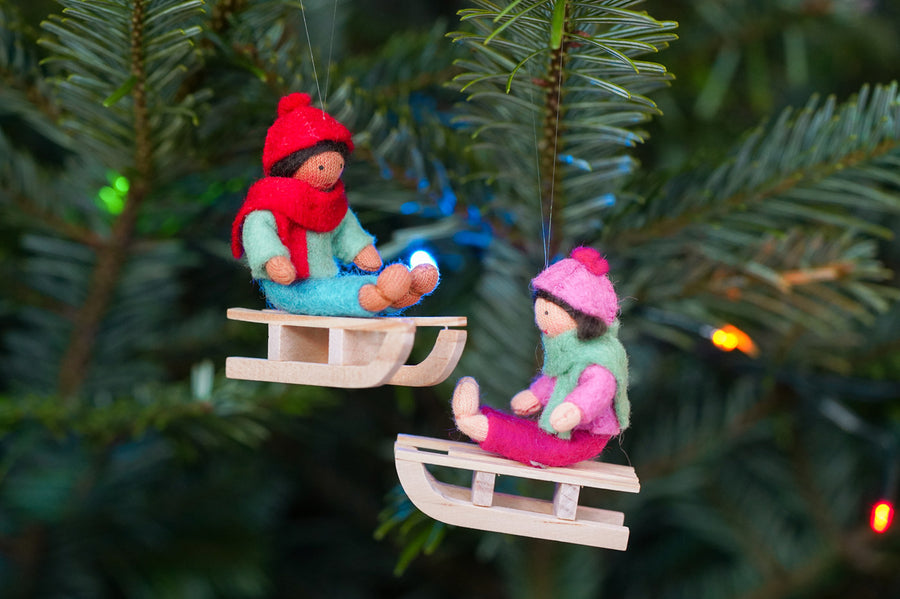 Close up of the Ambrosius handmade sledging boy and girl Christmas decorations hanging from a Christmas tree