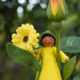 Close up of a yellow calendula Ambrosius felt fairy doll on a yellow flower in front of a green background