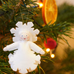 Ambrosius handmade felt snow crystal figure hanging in a Christmas tree in front of a slice of dried orange