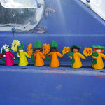 Ambrosius handmade sustainable felt dolls lined up on a blue metal background