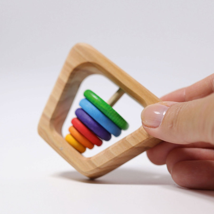 Grimm's Grasping Pyramid Rattle with an adult hand for scale