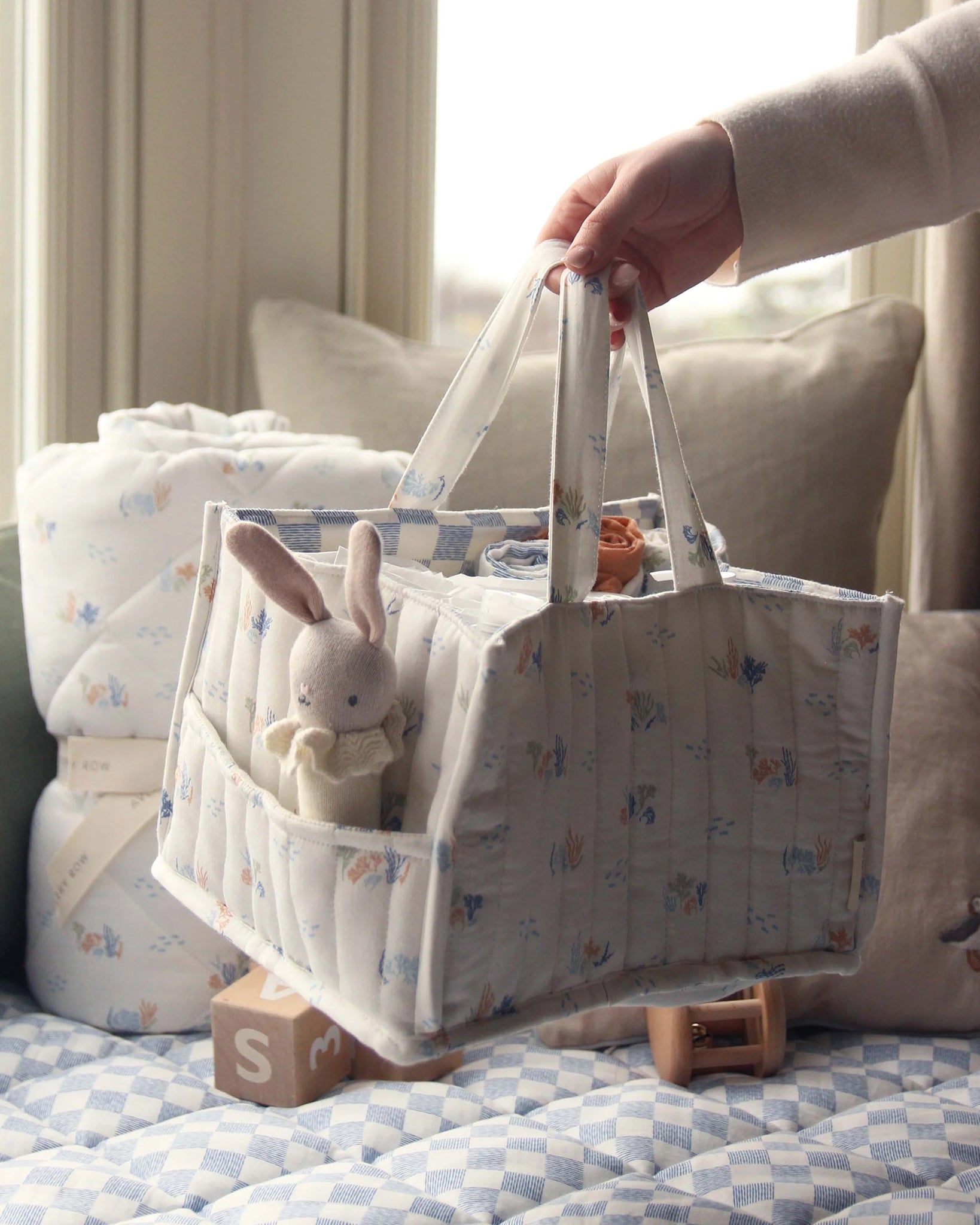 A person taking out a white and blue checked cloth from the Avery Row Organic Cotton Nappy Caddy Organiser - Coastlines