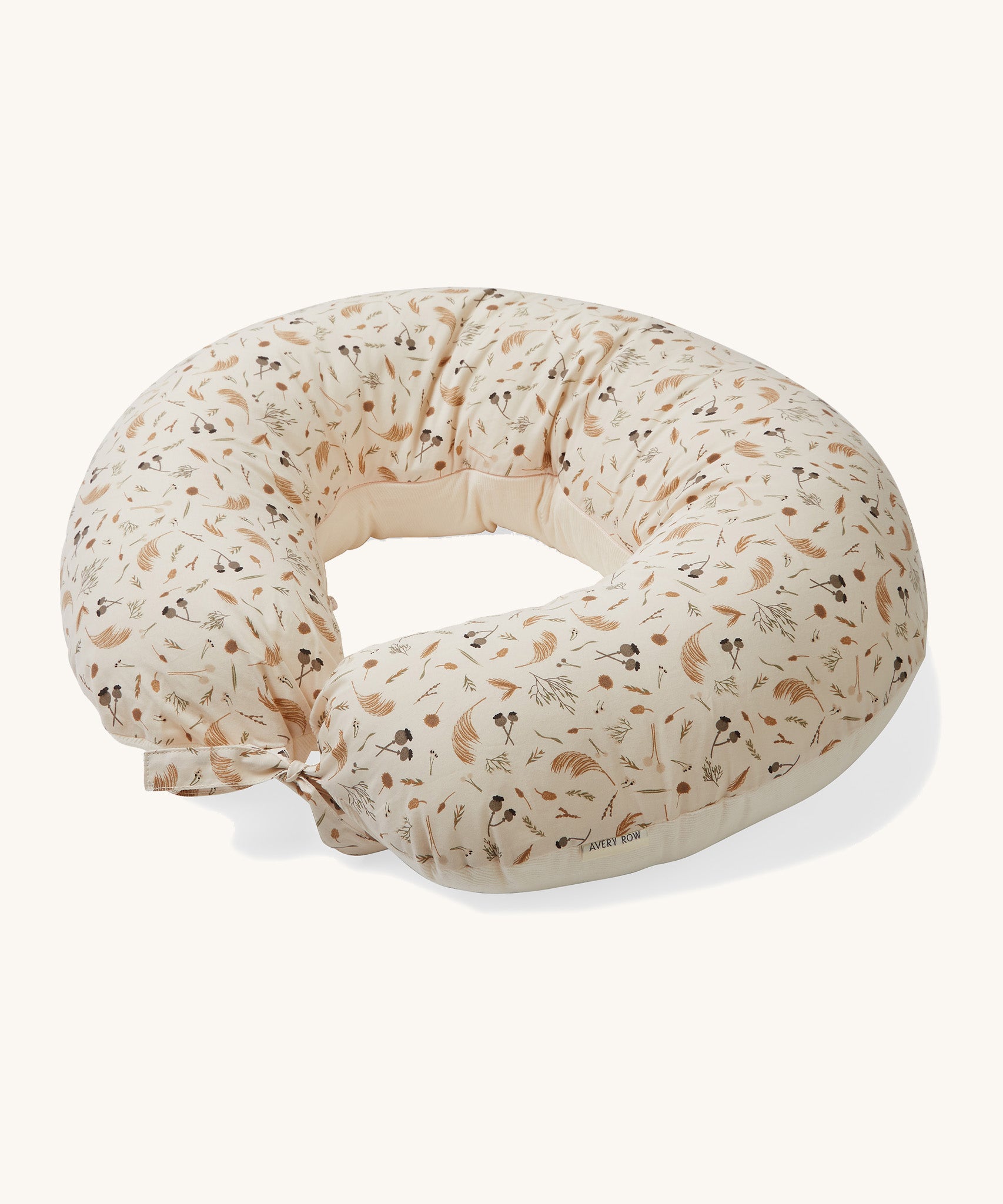 A soft light cream Avery Row nursing pillow with a grassland design on a cream background.