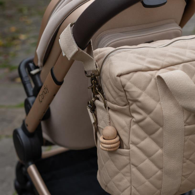 A close up of one of the pram clips attached to a pram with the Avery Row Baby Changing Bag in a  Natural colour attached. 