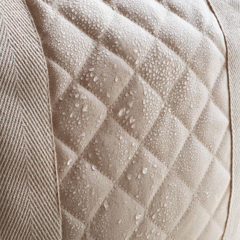 A close up of the water resistant quilted fabric on the outer of the Avery Row Baby Changing Bag in a  Natural colour