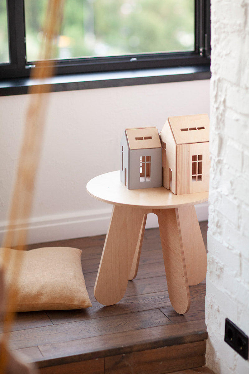 Babai eco-friendly wooden hollhouses on a wooden X stool in front of a garden window