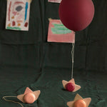 Babai sustainable wooden pull and go ship toys spread out on a green sheet below a red balloon