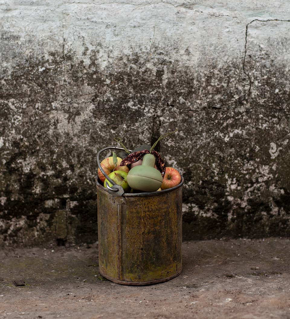 Metal bucket full of real fruit and a Babai sustainable wooden pear toy on the top