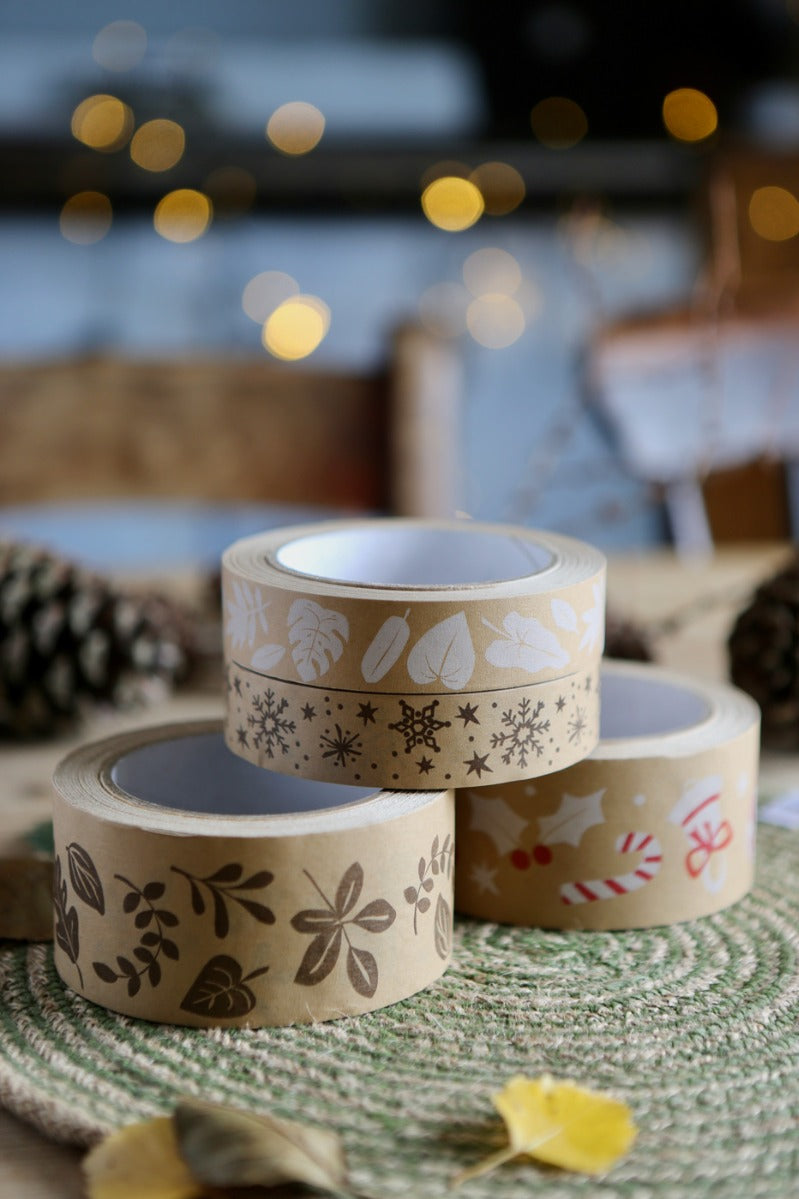 Close up of the Babipur brown eco kraft paper tapes in the Autumn leaf and festive prints on a green placemat