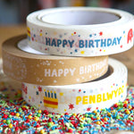 Stack of three babipur design eco paper tapes including colourful and kraft English Happy Birthday designs and Colourful Welsh Penblwydd Hapus design