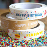 Stack of three babipur design eco paper tapes including colourful and kraft English Happy Birthday designs and Colourful Welsh Penblwydd Hapus design