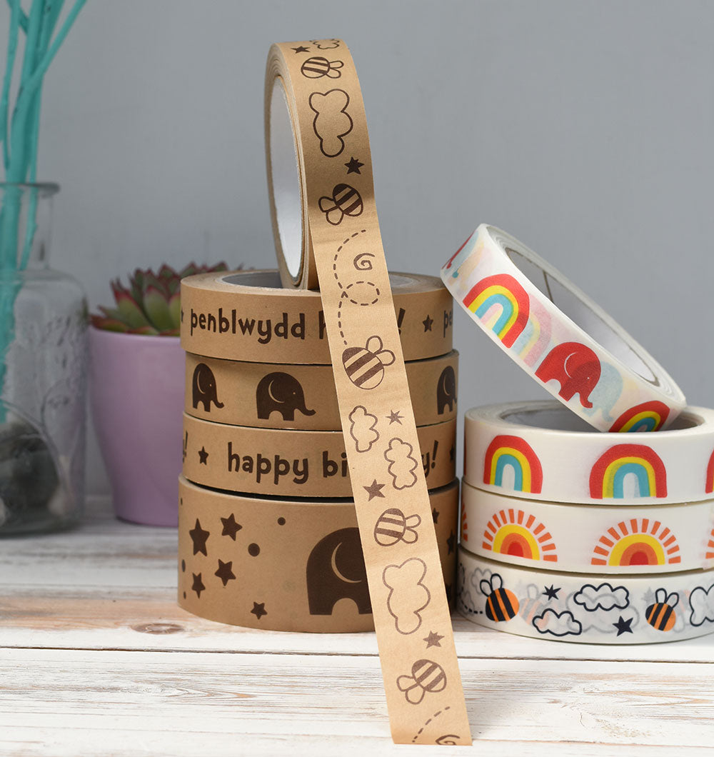 Two stacks of paper tape on a worktop. The tape on the top of the left stack has been pulled to reveal a bee design.