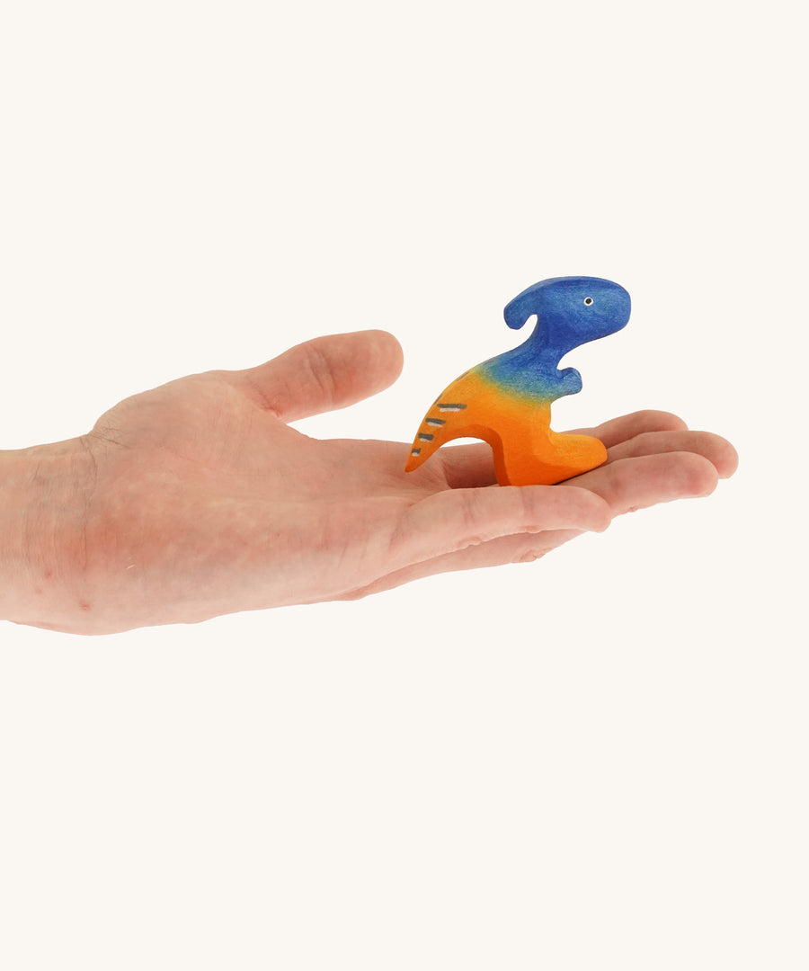 Blue and orange standing baby Parasaurolophus on a hand