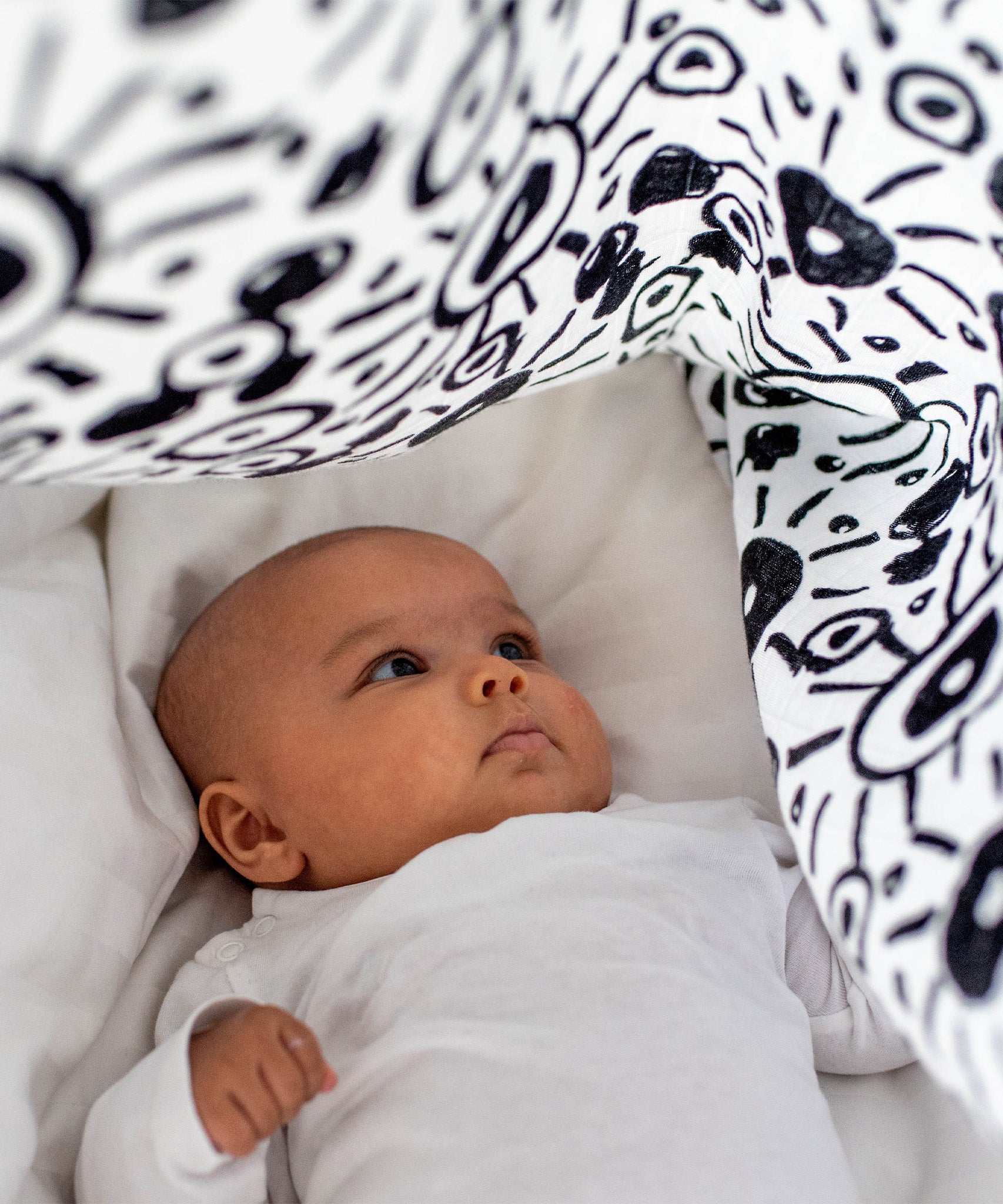 A child breastfeed with the parent using the muslin cloth on their arm/shoulder