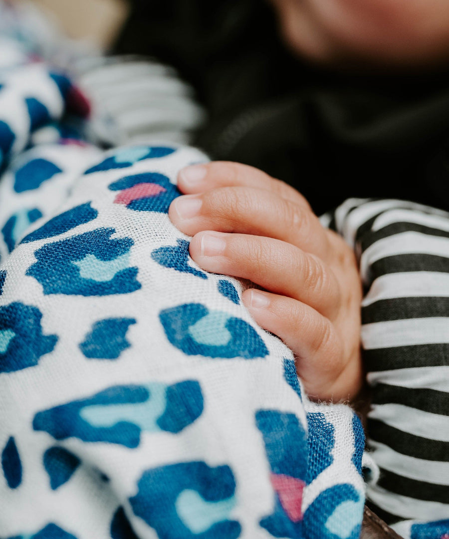 A baby looking up at the red and light blue Leopard print on the Etta Loves Organic Cotton Baby Muslin Squares 3 Pack - Leopard