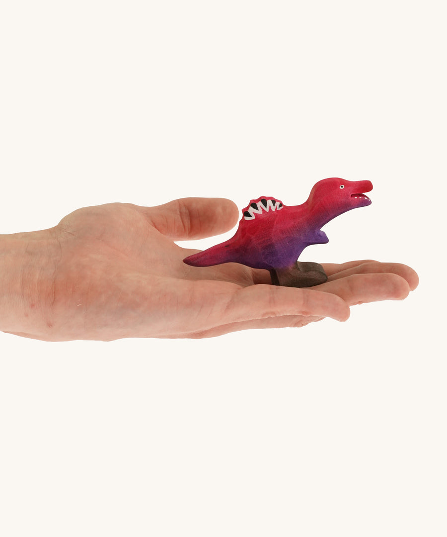 Pink and purple standing baby spinosaurus on a hand