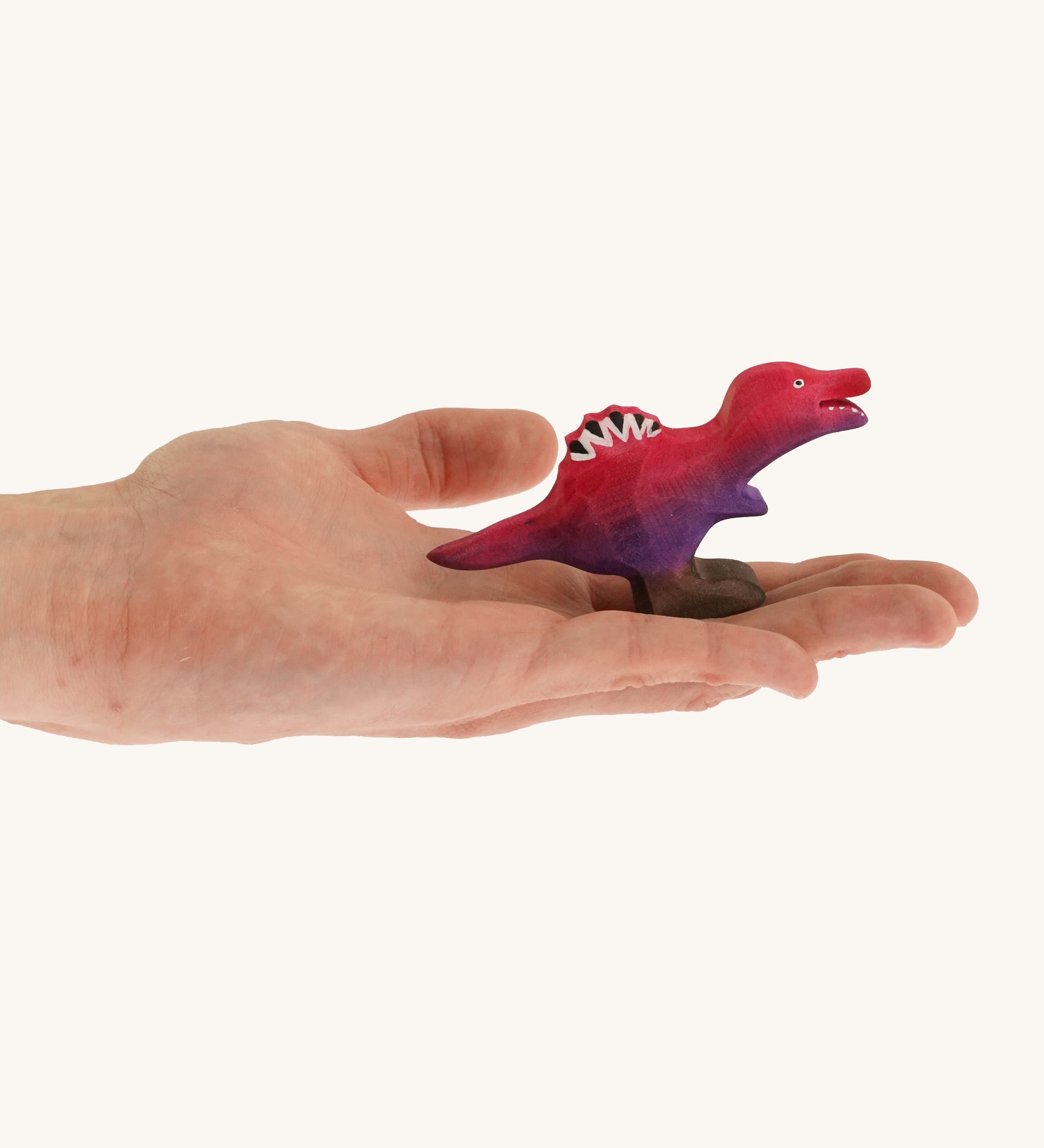 Pink and purple standing baby spinosaurus on a hand