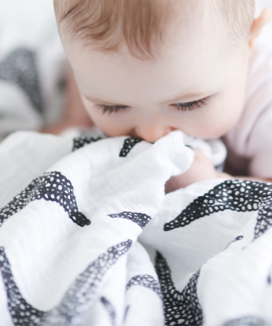 A child grasping the XL Starfish muslin cloth 