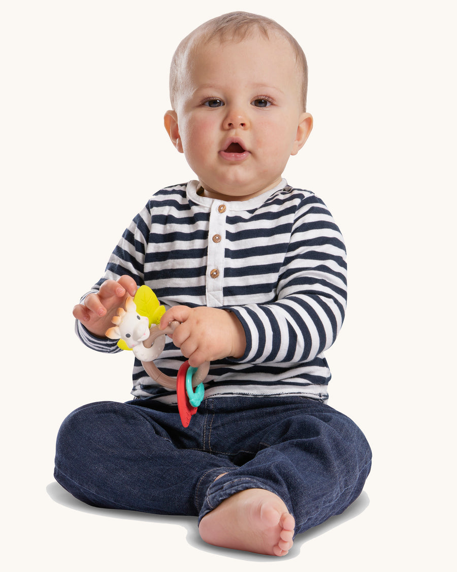 A child happily grasping and chewing on the Sophie The Giraffe - Nature Chew Rattle